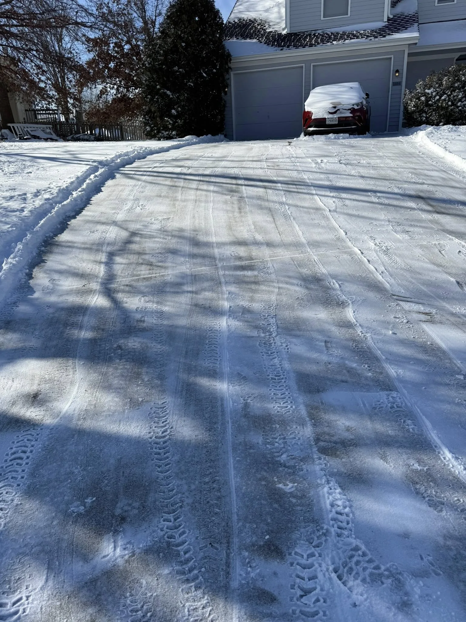 Residential driveway cleared after snow with tire tracks visible